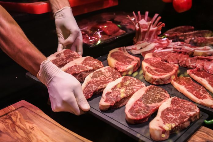 side view the chef makes preforms raw marbled beef for steaks on a stand